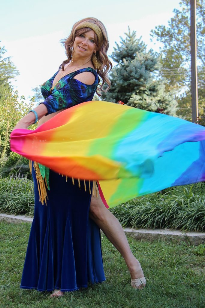 A woman swiriling a rainbow colored veil. 